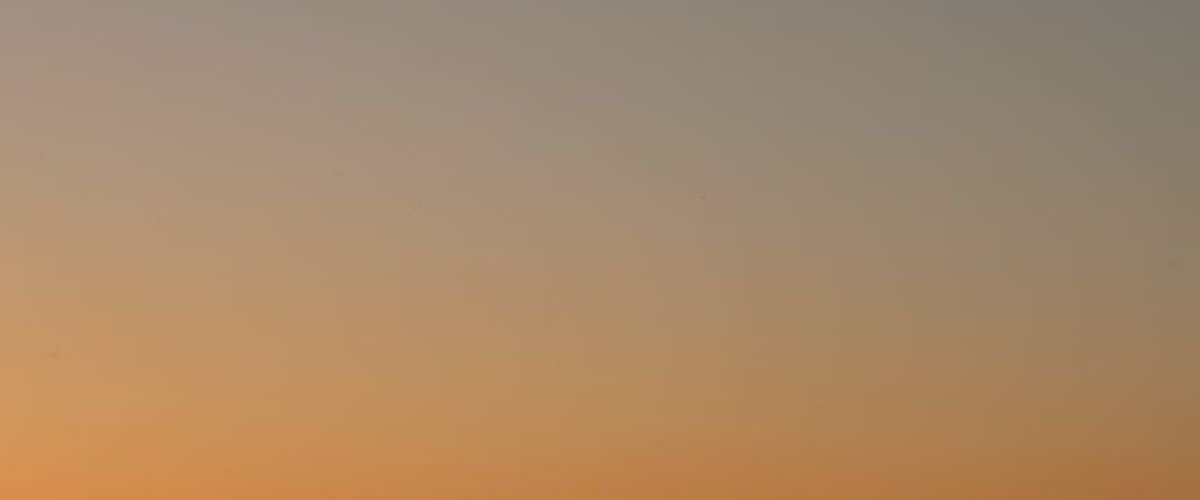 Panoramic view of a serene landscape with a person meditating at sunrise.
